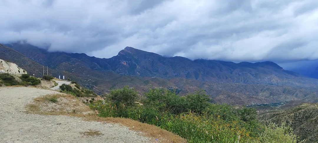 Camino de montaña tallado en la sierra árida bajo cielo nublado, evocando la carretera y el encuentro con uno mismo.